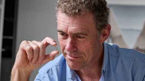 Simon Malpas carefully holds a small brain sensor between his thumb and forefinger