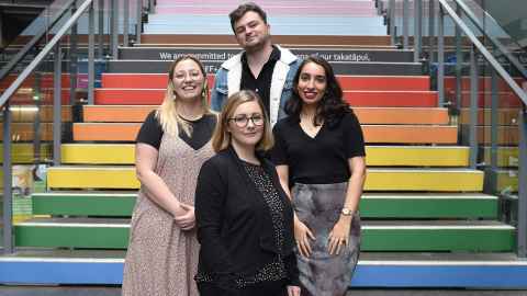 image of staff members standing by rainbow staircase